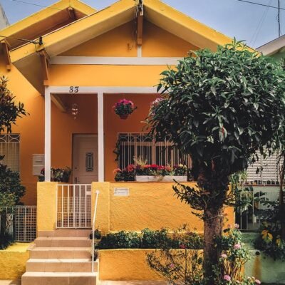 Bright yellow house with lush garden, vibrant flowers, and welcoming porch entrance.